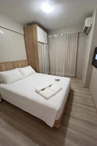a bedroom with a large bed with white sheets at Aquarius Flat 510 in Santa Cruz do Sul