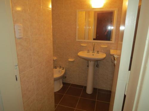 a bathroom with a sink and a mirror and a toilet at Hotel Trocadero in Necochea