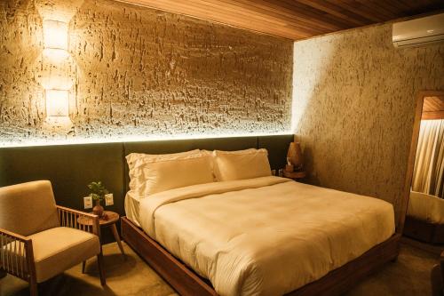 a bedroom with a large bed and a chair at Reserva Mazu in São Miguel dos Milagres