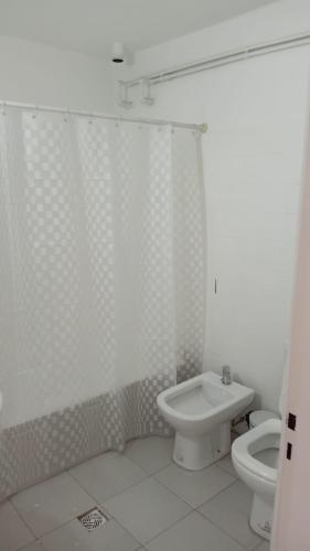 a white bathroom with a toilet and a sink at Departamento centro Gral Roca in General Roca