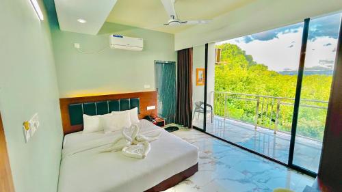 a bedroom with a bed and a balcony with a view at Cloudy Inn Resort in Bāndarban