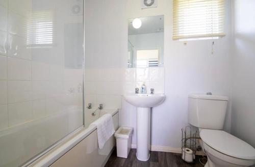 a white bathroom with a toilet and a sink at The Retreat Camber in Camber