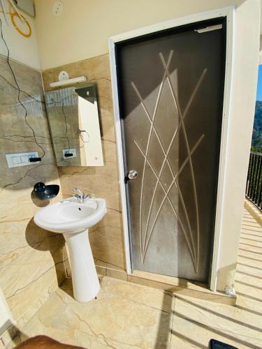 a bathroom with a sink and a shower with a door at Rivervalley View Homestay in Kandāghāt