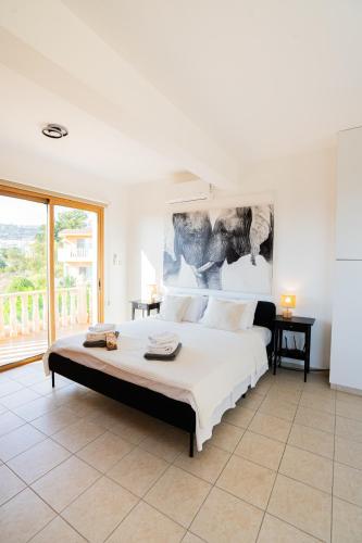 a bedroom with a large white bed with a large window at Casa Alba Modern Boho Villa with private Pool near to Sea, Paphos in Peyia