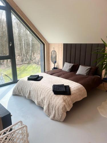 a bedroom with a large bed with a large window at Chill ChaTka Osowiec Las&SPA pod Warszawą in Osowiec