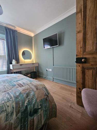 a bedroom with a bed and a tv on the wall at The Beaches - En-suite Rooms in Redcar