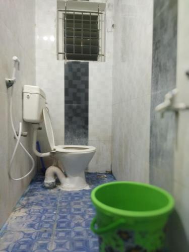 a bathroom with a toilet and a green bucket at Nomad in Coimbatore