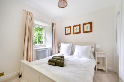 a bedroom with a white bed with two green towels on it at Idyllic Waterside Cottage in Mid Devon in Tiverton
