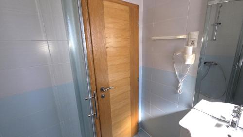 a bathroom with a shower with a wooden door at Rooms-Sobe Haus Magdalena Krk in Krk
