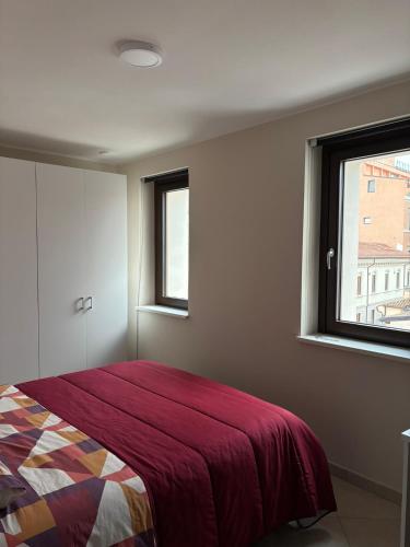 a bedroom with a bed with a red blanket and a window at Sirè House in LʼAquila