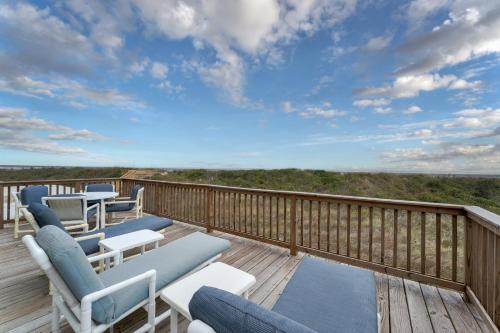 a deck with chairs and tables and a view of the ocean at 4110 - Coop's Cottage in Duck