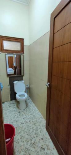 a bathroom with a toilet and a wooden door at Sabi House Sardjono in Yogyakarta