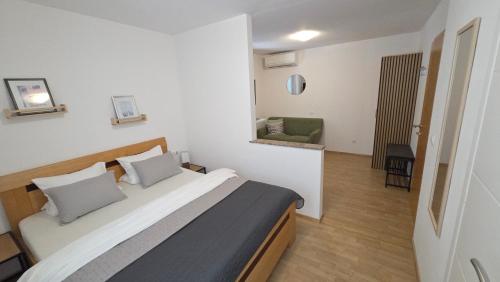 a bedroom with a large bed and a green chair at Rooms-Sobe Haus Magdalena Krk in Krk