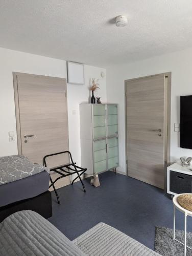 a bedroom with a bed and a tv and a chair at Gemütliches Zimmer in der modernen Ferienwohnung Schwalbennest im EG links in Sachsenheim