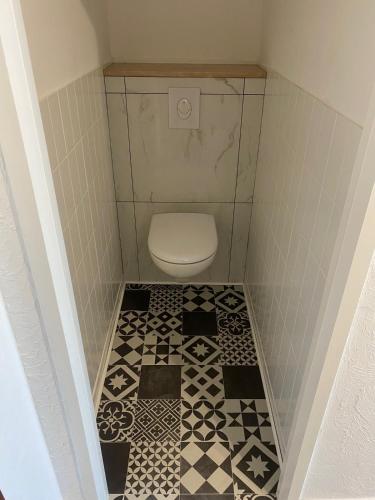 a small bathroom with a toilet with black and white tiles at - Le Belvédère - in Turckheim