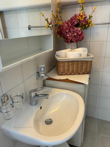 a bathroom with a sink and a basket of flowers at Le Petit Ruisseau in Ollon
