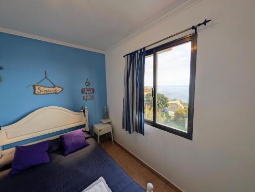 a blue bedroom with a bed and a window at Paul do Mar view in Paul do Mar