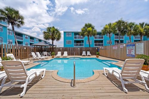a swimming pool with lounge chairs and a blue building at Coastal Condo Steps from the Beach in Gulf Shores