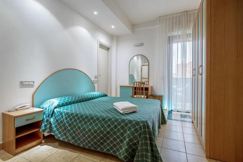 a bedroom with a bed with a green bedspread at CASA MAJOR Hotel & Appartamenti CERVIA in Cervia