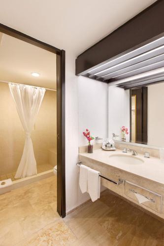 a bathroom with a sink and a large mirror at El Cid Granada Hotel & Country Club in Mazatlán
