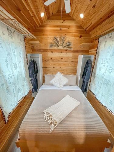 a large bed in a wooden room with windows at The Self-Care Tiny Cabin in Parsons