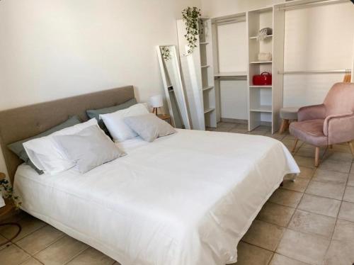 a bedroom with a large white bed and a pink chair at Maison RG in Torre Canne