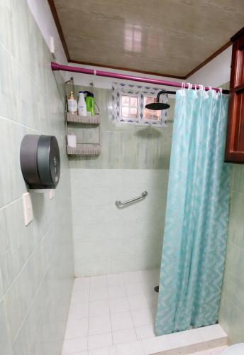 a bathroom with a shower with a blue shower curtain at Greenhouse in Almirante