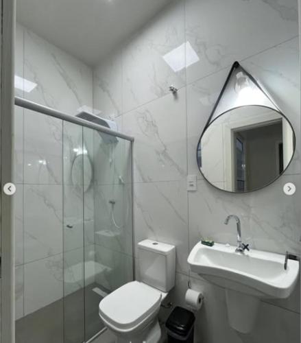 a bathroom with a toilet and a sink and a mirror at N 40 - Central com 2 quartos, ar condicionado e garagem in Cascavel