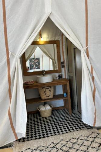 a bathroom with a sink and a mirror at Hidden luxury Camp in Merzouga