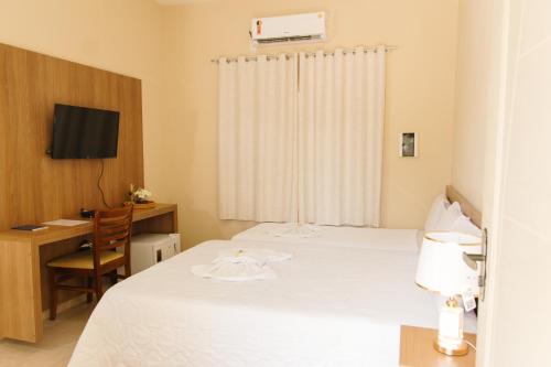 a room with two beds and a desk and a television at Paramirim Palace Hotel in Paramirim