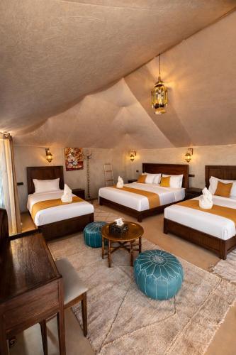 a large room with two beds and a table at Hidden luxury Camp in Merzouga