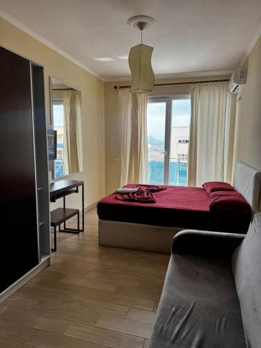 a bedroom with a bed and a desk and a window at Inis apartamans -50 m from beach in Shëngjin