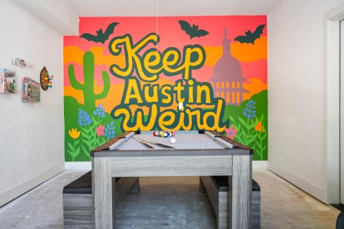 a ping pong table in a room with akeep autism world mural at Spacious 5BR Central Austin Home Sleeps 13 in Austin