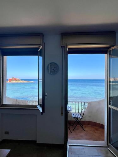 a room with two sliding doors with a view of the ocean at La terrazza sul mare, 44 in Marzamemi