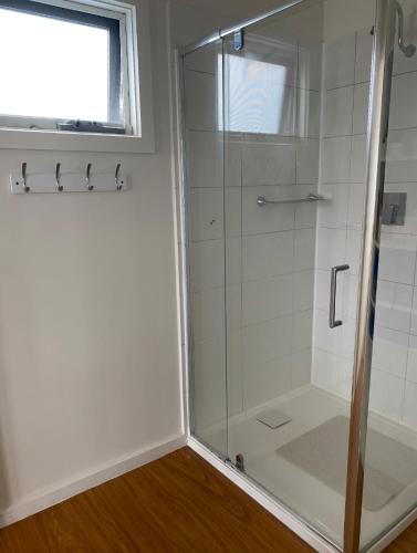 a shower with a glass door in a bathroom at Coronet Bay Beach Cabin in Coronet Bay