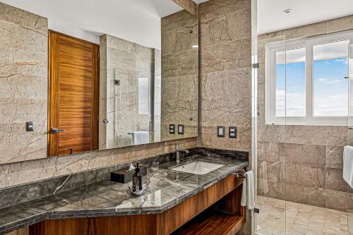 a bathroom with a sink and a mirror at Modern condo with ocean views, rooftop infinity pool & central AC in Puerto Vallarta
