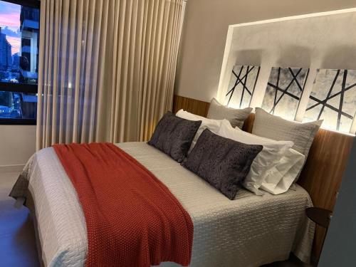 a bedroom with a bed with a red blanket on it at Studio moderno e confortável no Marista in Goiânia
