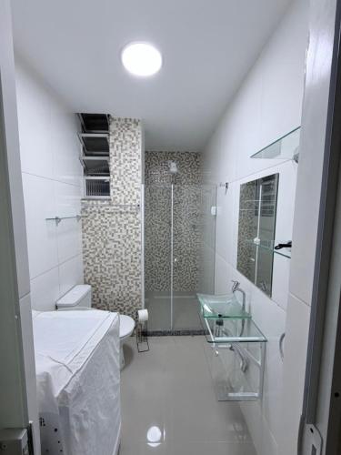 a white bathroom with a shower and a sink at Studio 302 Centro Imperial in Petrópolis