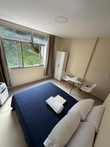 a bedroom with a blue bed and a table at Studio 302 Centro Imperial in Petrópolis