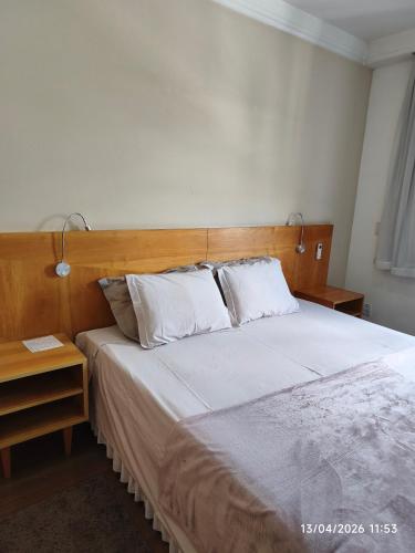 a bedroom with a large bed with a wooden headboard at Apart Hotel 48 in Mogi das Cruzes