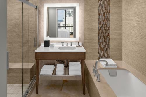 a bathroom with a sink and a tub and a mirror at The Westin Crystal City Reagan National Airport in Arlington