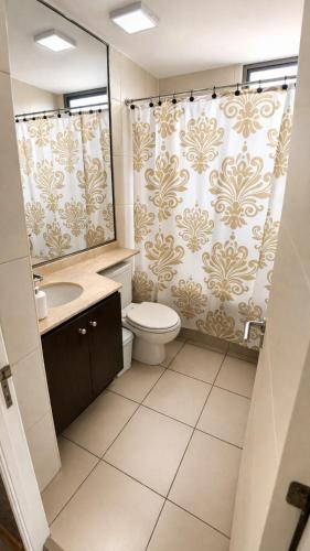 a bathroom with a toilet and a shower curtain at Departamentos Mar Egeo in Iquique