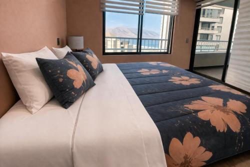a bedroom with a large bed with a large window at Departamentos Mar Egeo in Iquique