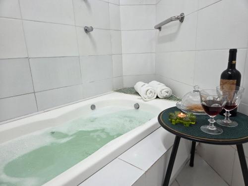 a bath tub with a table with wine glasses at Flat 01 Carvalhos de Aldeia km5 in Recife