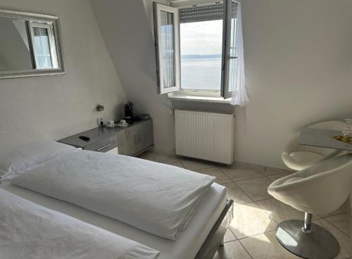a white bedroom with a bed and a window at Hotel la Perla in Meersburg