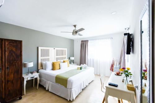 a bedroom with a large white bed and a desk at Hotel Siesta Holbox in Holbox Island