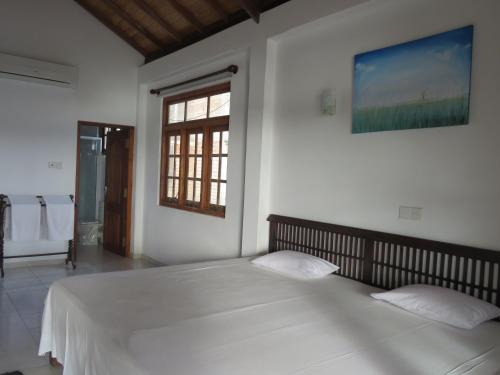 a bedroom with a large white bed with a window at Paradise Bay in Beruwala