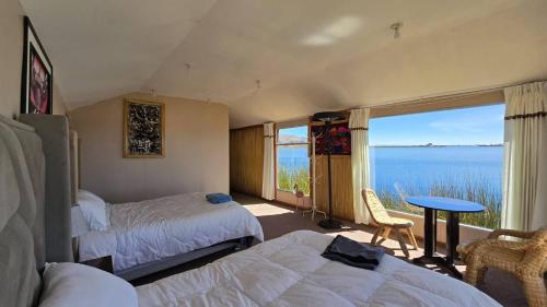 a bedroom with two beds and a view of the ocean at Uros Sunset Lodge in Puno