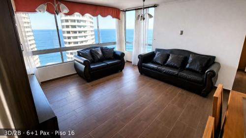 a living room with two black leather chairs and a large window at Departamentos Nautilus in Iquique