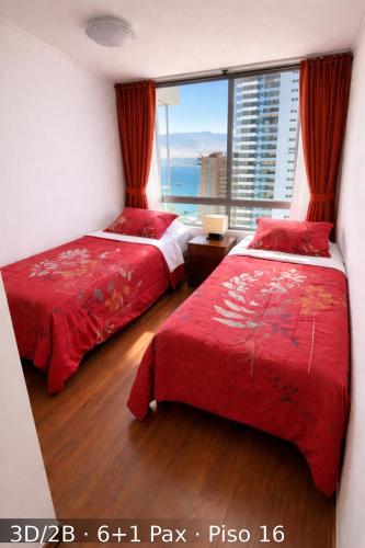two beds in a room with a large window at Departamentos Nautilus in Iquique
